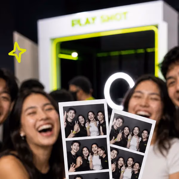 Friends laughing behind their fresh photo strips