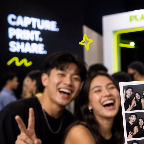 Two friends laughing at the booth, one throwing a peace sign