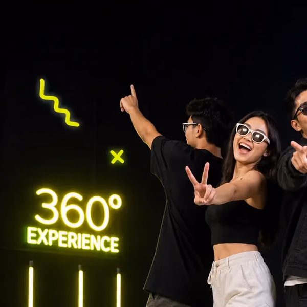Friends posing on the 360° platform beside the neon sign