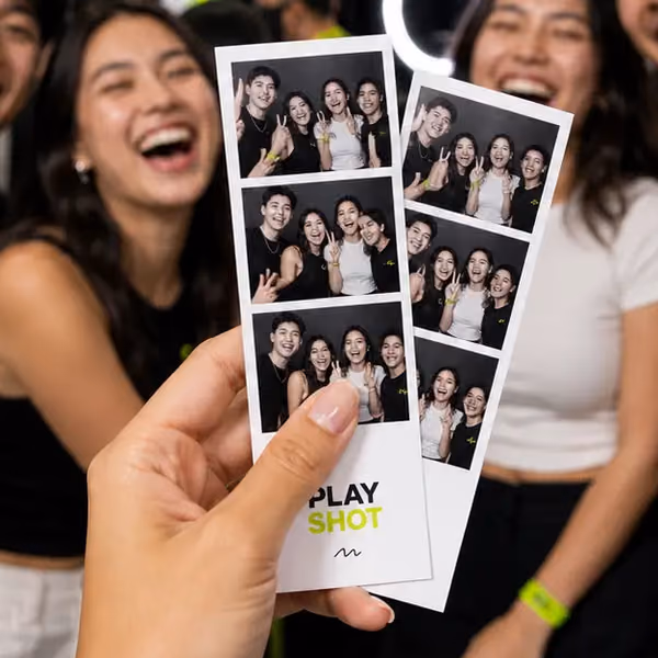 A hand holding up a PlayShot photo strip in front of the group