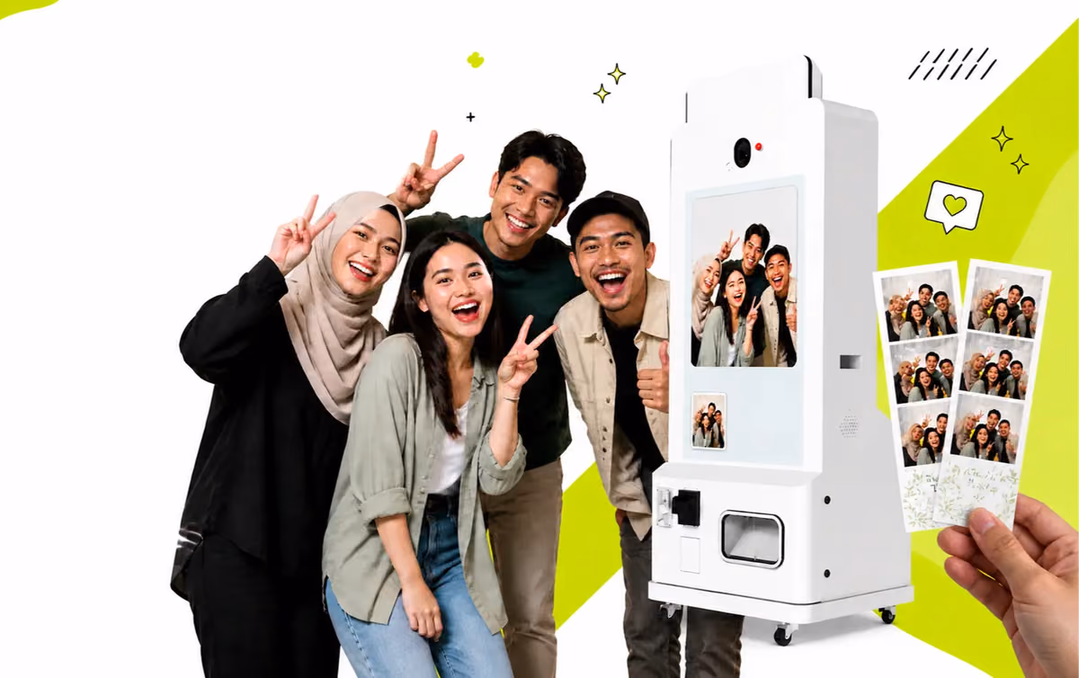Friends posing beside the PlayShot print booth, a hand holding their strips